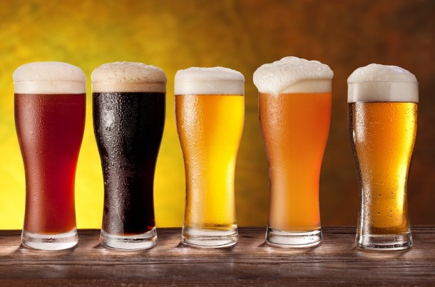 Assortment of beer glasses with a wooden barrel. Background - dark yellow gradient.